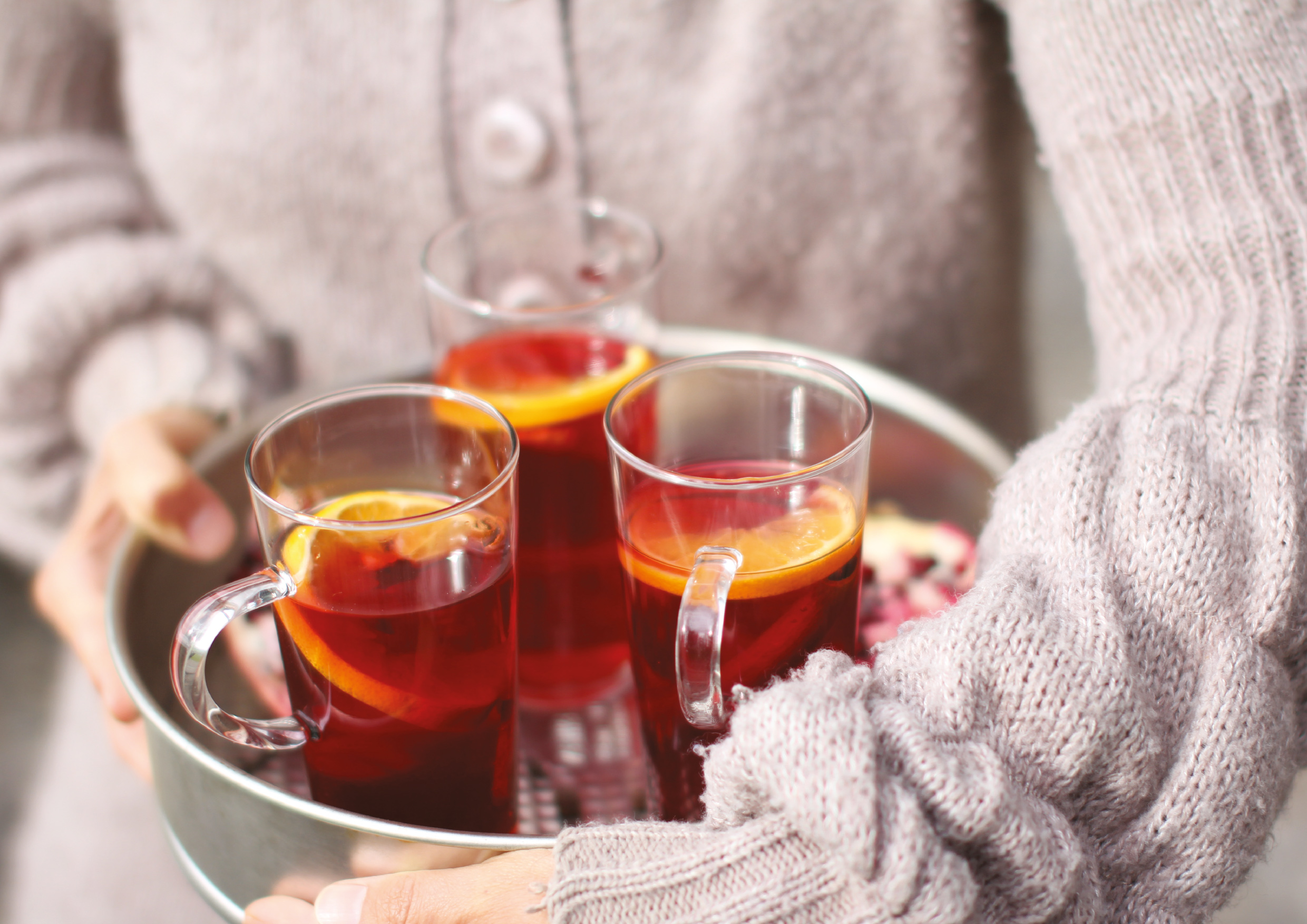 Frau in Strickjacke hält Tablett mit heißen Getränken, Inhaltsseite aus dem Herbstjournal 2026