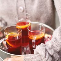 Frau in Strickjacke hält Tablett mit heißen Getränken, Inhaltsseite aus dem Herbstjournal 2026